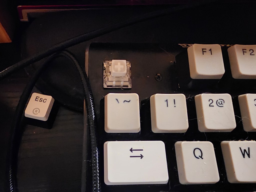 A Hexgears GK735 keyboard with the Escape keycap removed exposing the switch stem.