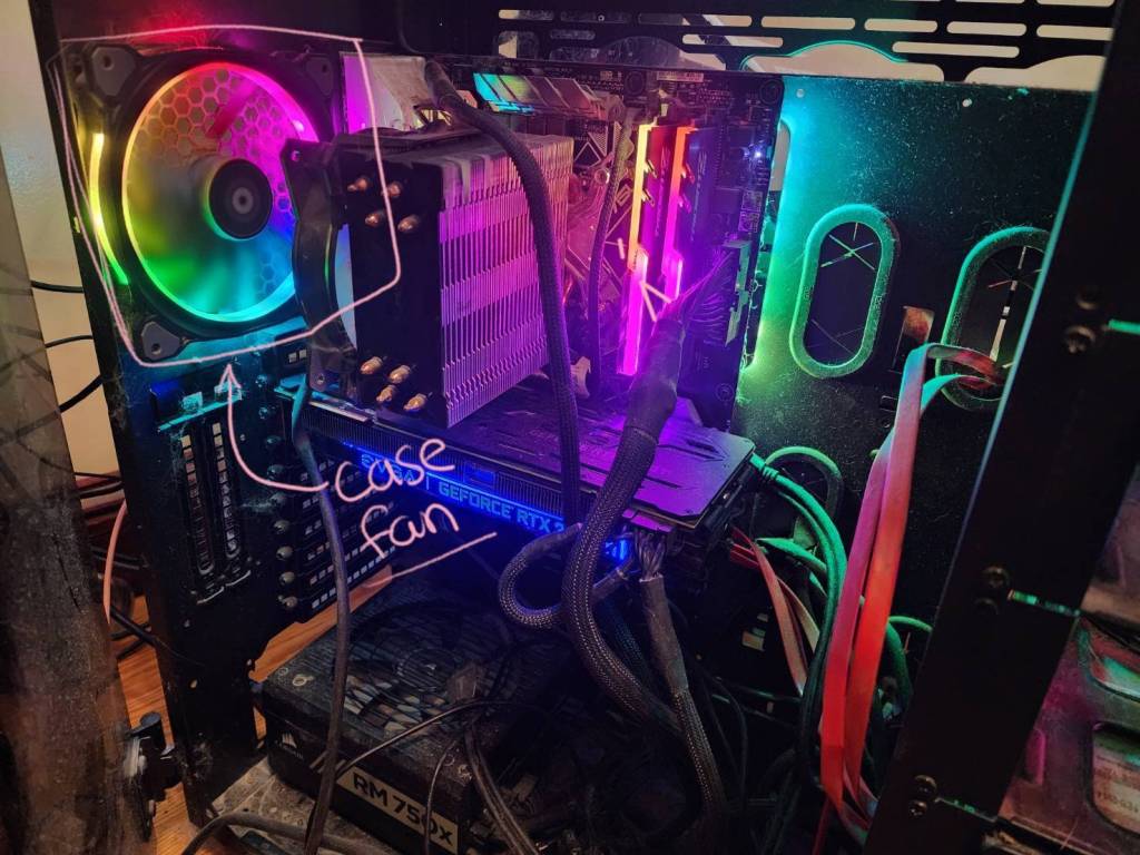 An image of the inside of a custom built PC with rainbow LEDs with the case fan visually highlighted.